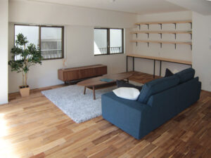 アカシア無垢フローリングと壁面収納棚を備えたリビング。ラスティックグレード特有の節と色幅が空間に表情を与えている。