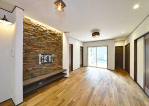 テレビ背面に天然石タイルを施工し、アカシア無垢フローリングと組み合わせたリビング