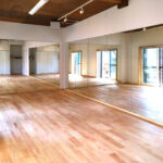 大きな鏡張りのあるダンスフロアと無垢フローリングの空間