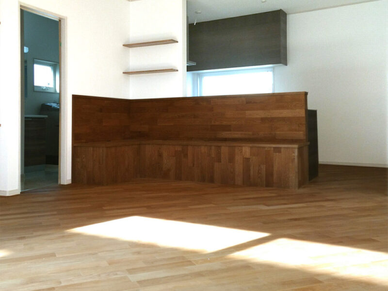 キッチンカウンターと一体になったオーク無垢材のベンチとフローリング