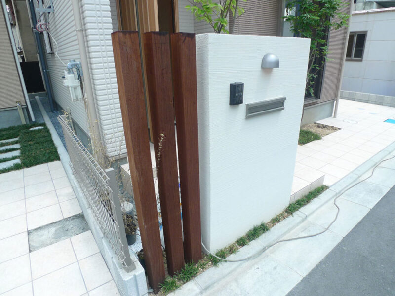 白い門壁とウリン材の縦格子が調和した外構デザイン