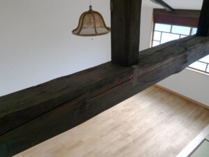 梁の存在感とフローリングが際立つ古民家リノベーションの室内