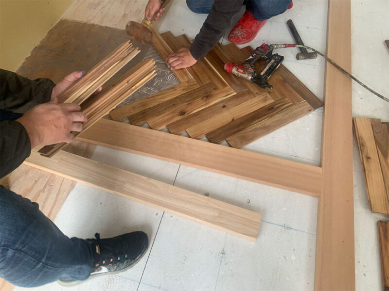 アカシアヘリンボーン無垢フローリングの割付確認を行う職人の作業風景