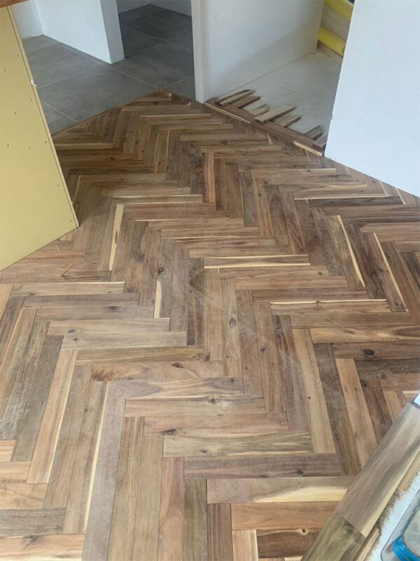 アカシア ヘリンボーンフローリングが広がるリビングダイニングの床施工風景