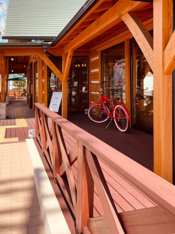 セランガンバツのウッドデッキに映える赤い自転車とログ調外観