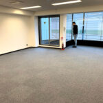 大きな窓とカーペットフロアの改修前オフィス