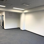 白い壁とカーペット敷きのオフィス通路