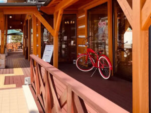 セランガンバツ材の手すりと赤茶色のウッドデッキ、奥に広がる店舗外観