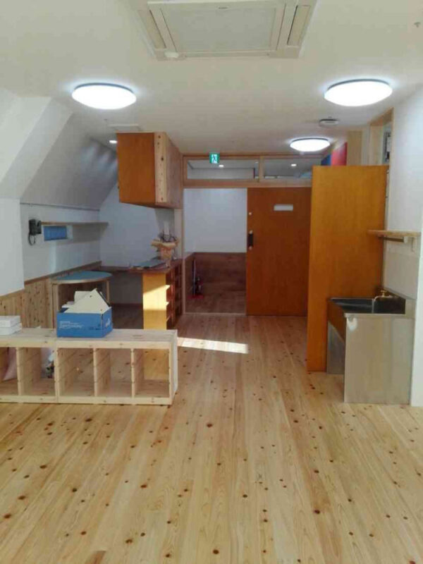 三重県産ヒノキ無垢フローリングを施工した教室入口側の様子。明るく温もりある木の質感が広がる。