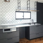 白いタイルと黒い収納が映えるシステムキッチン