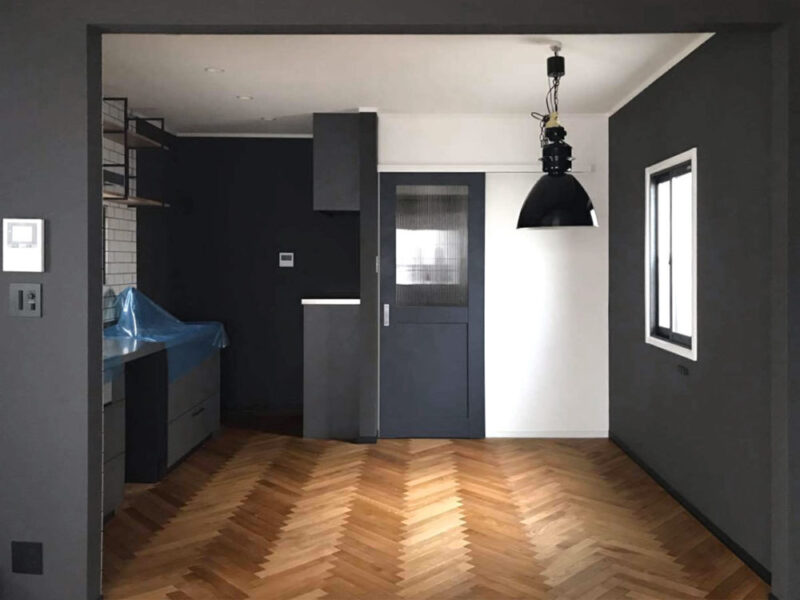 黒を基調とした壁と木目のヘリンボーンフローリングのコントラスト