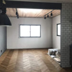 白壁と大きな窓を備えたリビングのヘリンボーンフローリング