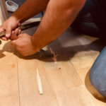 無垢フローリングをノミと金槌で剥がしている職人の作業風景