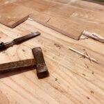 無垢フローリング撤去で使う工具（ノミと金槌）が下地合板に置かれている
