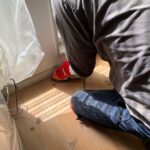 マウスサンダーでフローリングの端部を研磨する職人