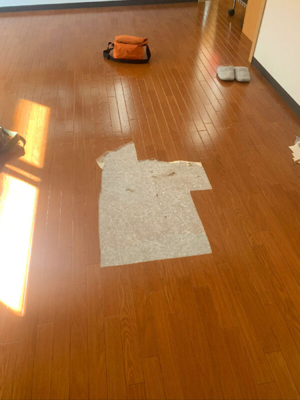 クッションフロアの一部を剥がした後の室内全景。床下地が部分的に露出している。