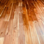 塗装途中のフローリング。左側は未塗装、右側は塗装済みで色が濃い。