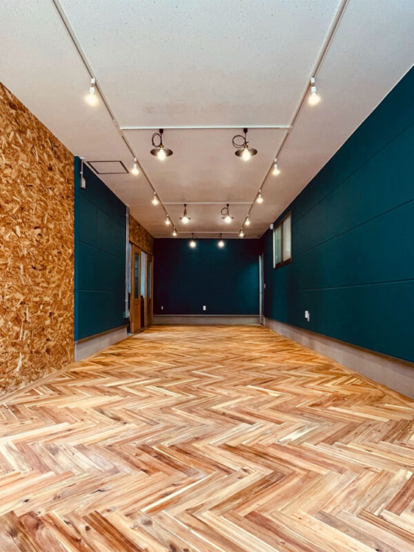 アカシア無垢フローリングを施工した店舗の内装、OSB壁とブルーの壁が特徴的な空間