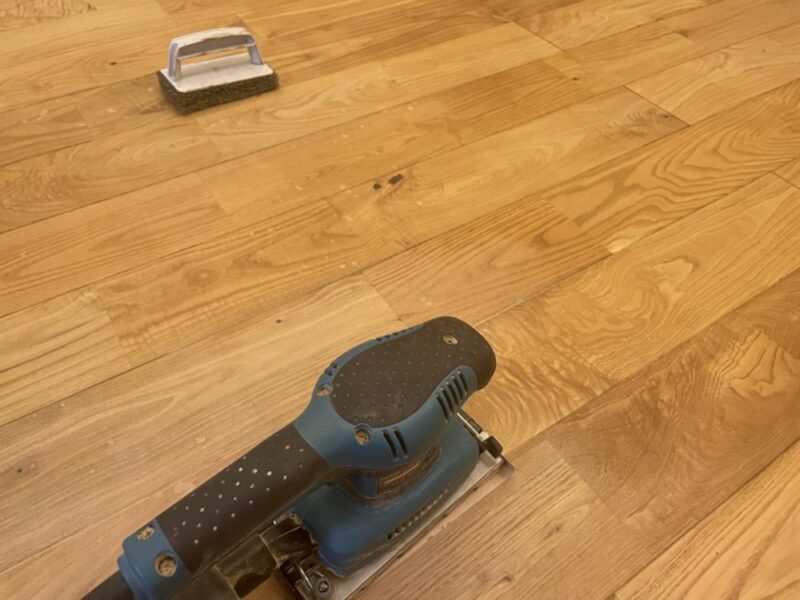 サンダーを使って無垢フローリングの表面を研磨している様子