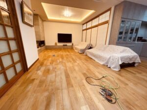 広いリビングでチェスナット無垢フローリングをサンディングしている光景