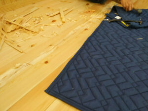 床暖房上の割れた無垢フローリングをノミで撤去する大工の作業風景