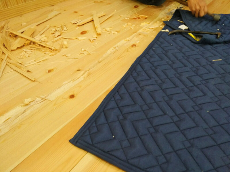 床暖房上の割れた無垢フローリングをノミで撤去する大工の作業風景