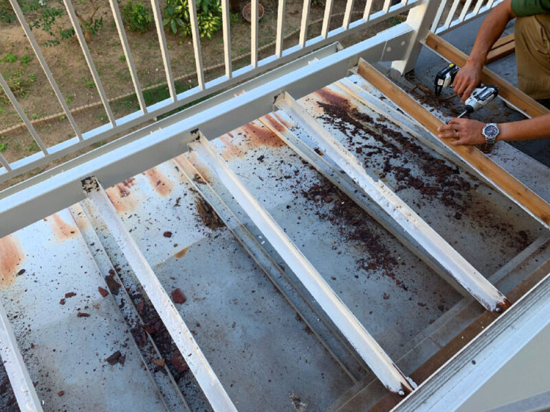 バルコニーのデッキ下地に残る錆を清掃している様子