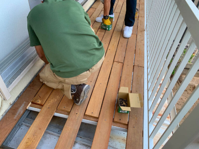 職人が二人でセランガンバツ材を張り進めている施工中の様子