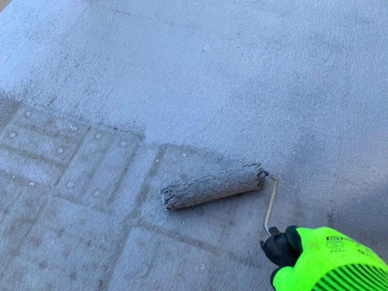 防水塗料をローラーで塗布している作業中の様子