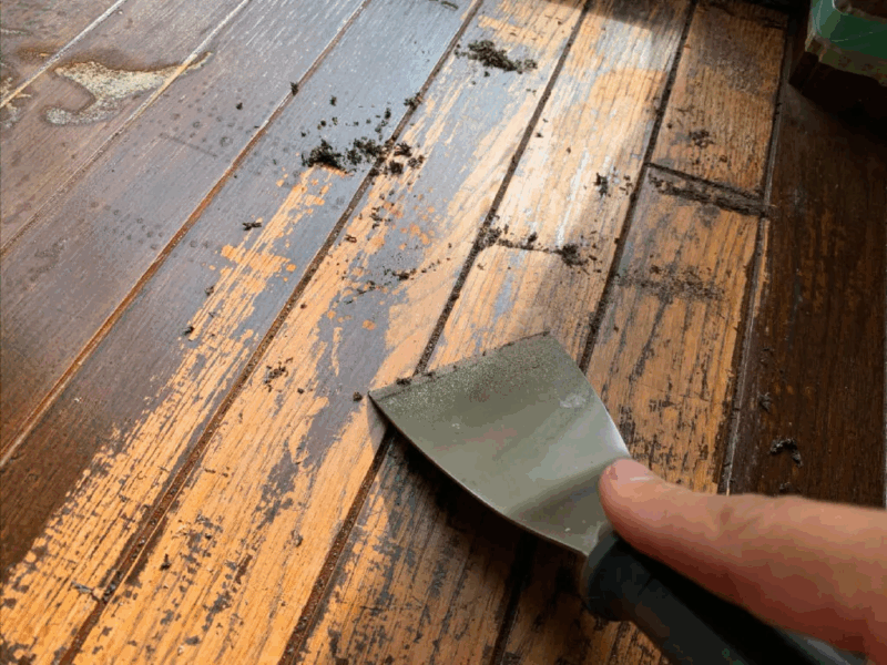 スクレイパーで無垢フローリングのワックスを丁寧に除去する作業