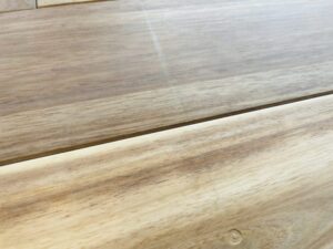 建具の設置時にできた引きずり傷が残るアカシア無垢フローリングの表面。