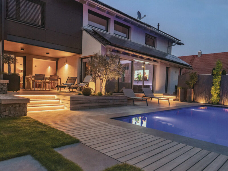 プールサイドに施工されたパドウク（カリン / 花梨）のウッドデッキ。柔らかな照明が映える夜のテラス。