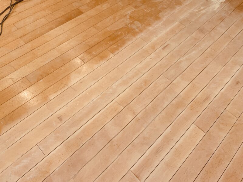 古い塗膜を除去中のフローリング。削り残しと素地部分の対比が見える状態