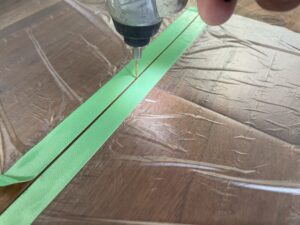 ブラックウォルナットのフローリングにドリルで穴を開けて床鳴り補修を行う作業の様子