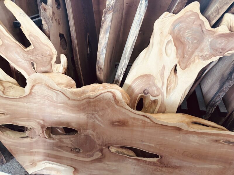 複数のカイヅカイブキの一枚板が立てかけられている様子。力強い木目が際立つ