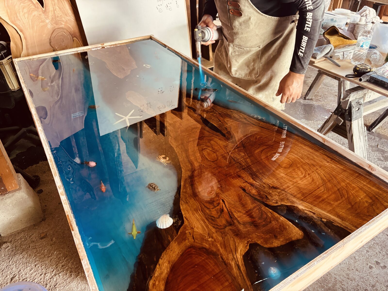 レジンテーブルにバーナーで仕上げの処理をしている様子