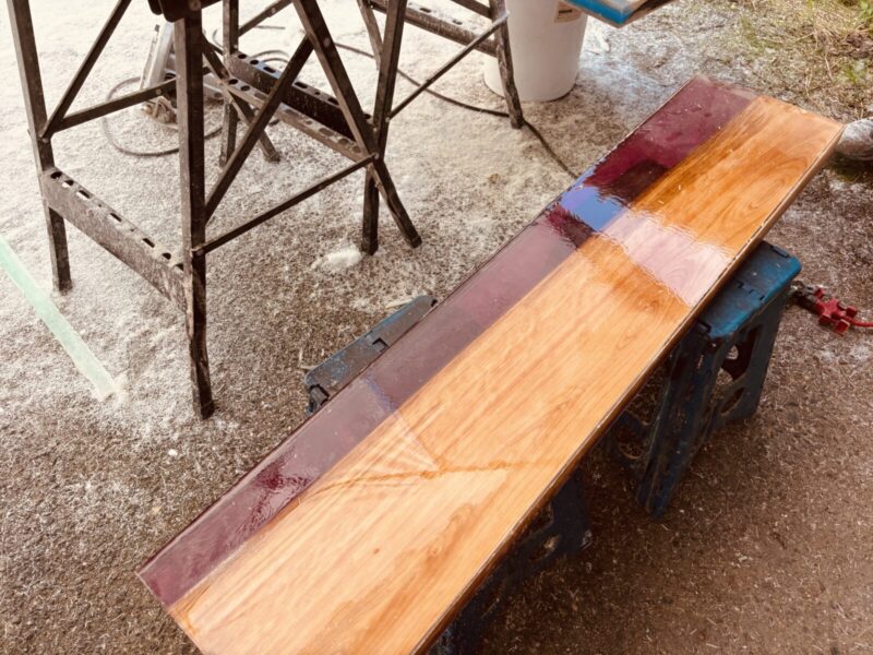 ヒノキとワインレッドレジンを組み合わせたテーブルを磨く様子