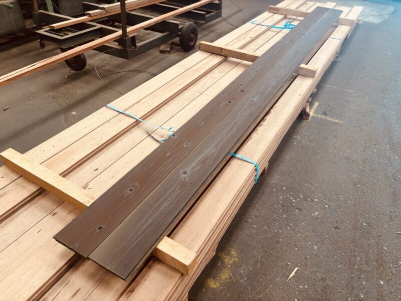 工場内で並べられた長尺の焼杉板。焦茶塗装済みで外壁材として使用可能。