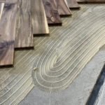 下地に接着剤を塗布して無垢フローリングを直貼り施工している現場写真