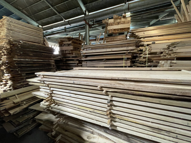 大きな倉庫内にさまざまな厚みの無垢材が桟積みされて並んでいる。広葉樹の厚板や幅広材が乾燥工程を待っている状態。