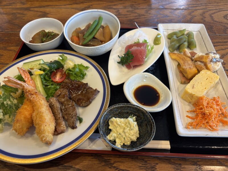 奈良県御所市のさんろくカフェのランチプレート。エビフライ、牛肉のソテー、サラダ、煮物、刺身、小鉢などが色とりどりに並んだ和定食。