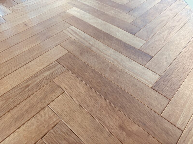 ヘリンボーン張りのオーク無垢フローリング。研磨前で全体的に黒ずみや使用感が見られる状態。