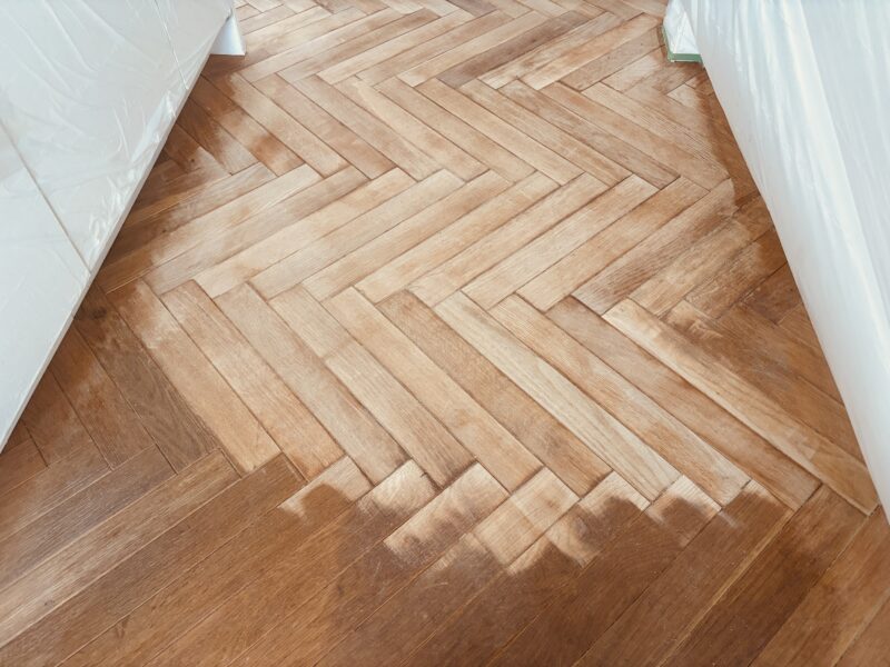 研磨作業が進み、明るい色味の素地が多く露出したヘリンボーンフローリング。
