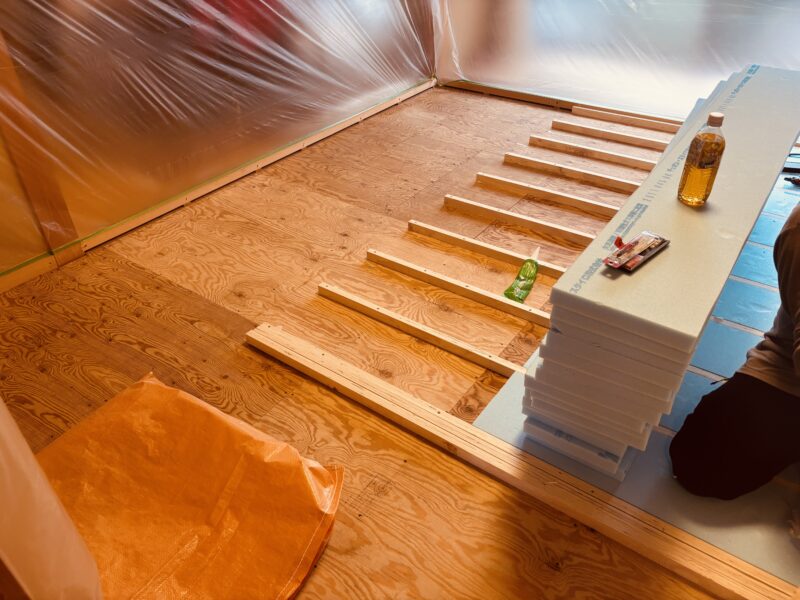 LVLとスタイロフォームを使った和室の床下地づくり。畳撤去後の8畳間で大工が高さを調整しながら下地を組んでいる様子。