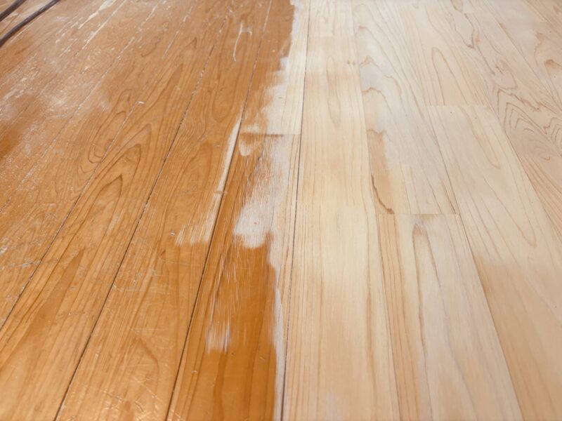 ヒノキ無垢フローリングを研磨して再生している途中の様子。右側は削りたての明るい木肌、左側は経年劣化した古い塗膜が残っている状態。