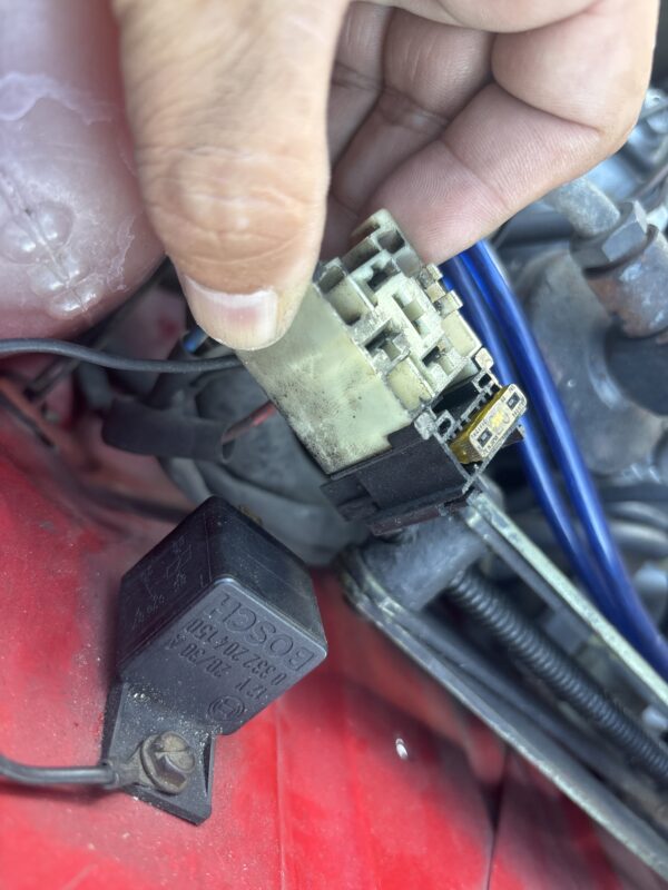 ルノー4のエンジンルーム内でヒューズボックスを点検する手元の写真