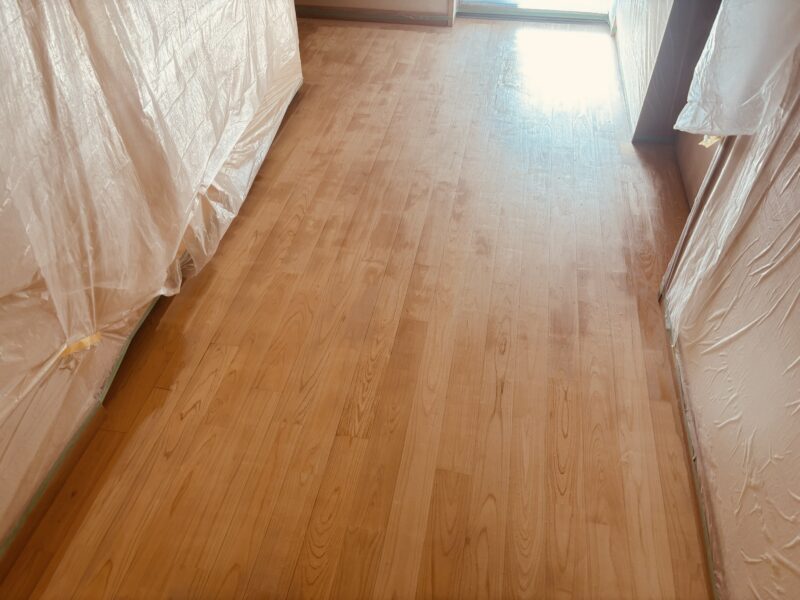 研磨を終え、素地のヒノキが柔らかく光を反射する廊下。養生シートに囲まれた作業現場の全景