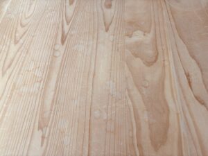 杉フローリング全体に輪じみや細かな傷が多数残り、白濁が広がっている施工前の状態。木目がくすみ、部分的に濃い汚れも見られる。