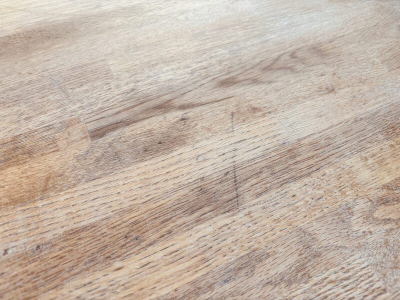 塗膜が摩耗し細かな傷や汚れが目立つ木製テーブル天板表面の拡大写真