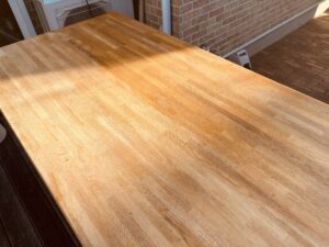 木製テーブル天板の研磨中の様子で、左側が研磨済み、右側が未研磨の比較写真